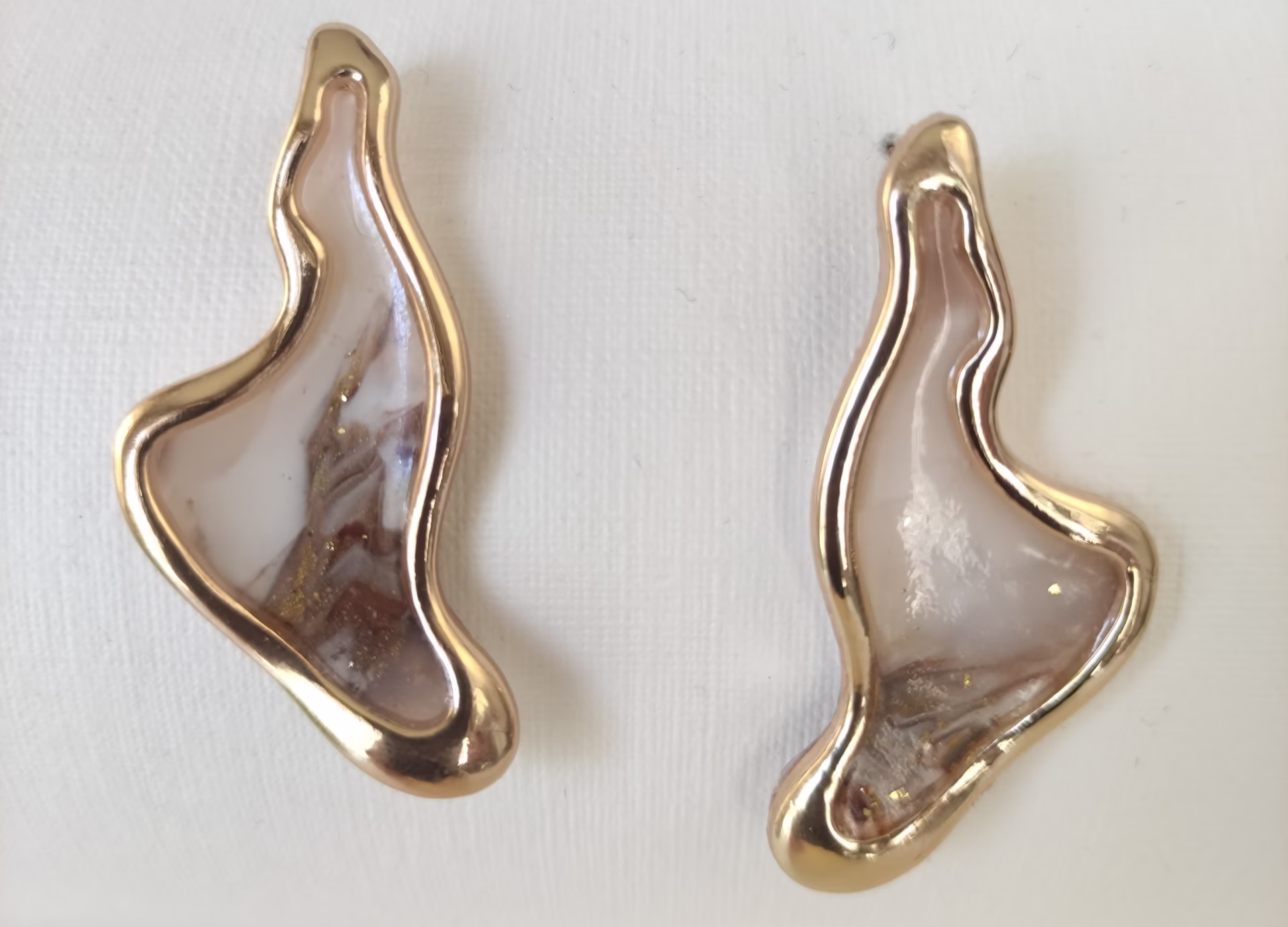 Brincos artesanais assimétricos com moldura dourada e interior marmoreado em tons de branco e dourado – Way of Love