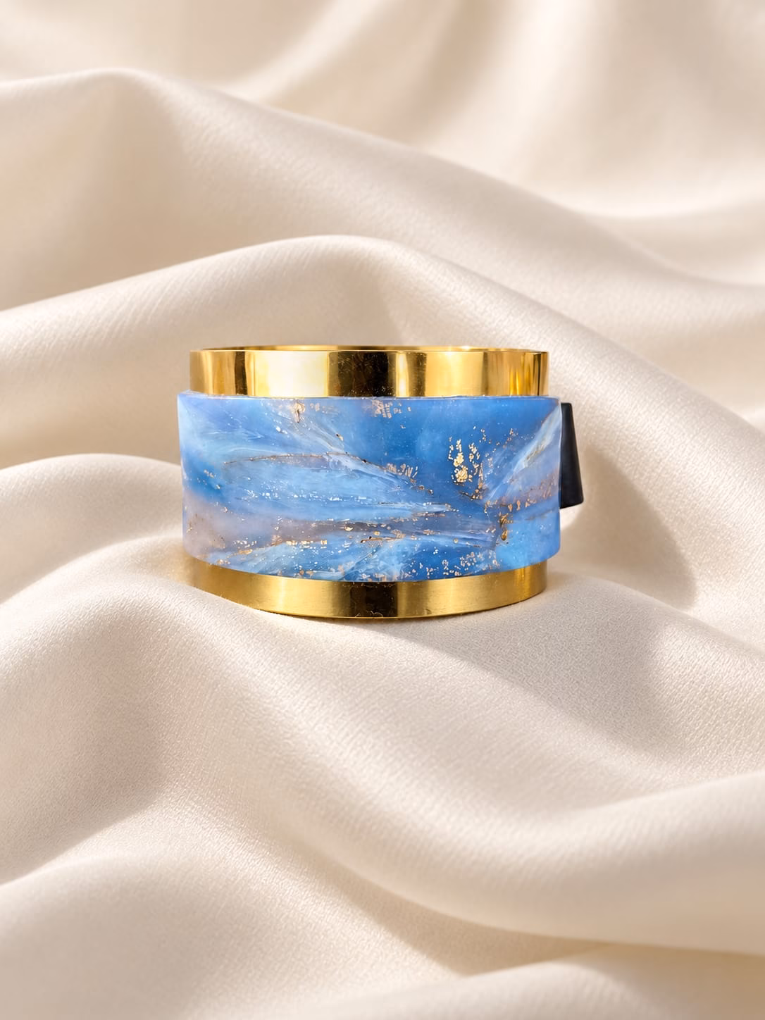 Pulseira Noa com aço inoxidável dourado, base preta e argila polímera azul e lilás com apontamentos dourados